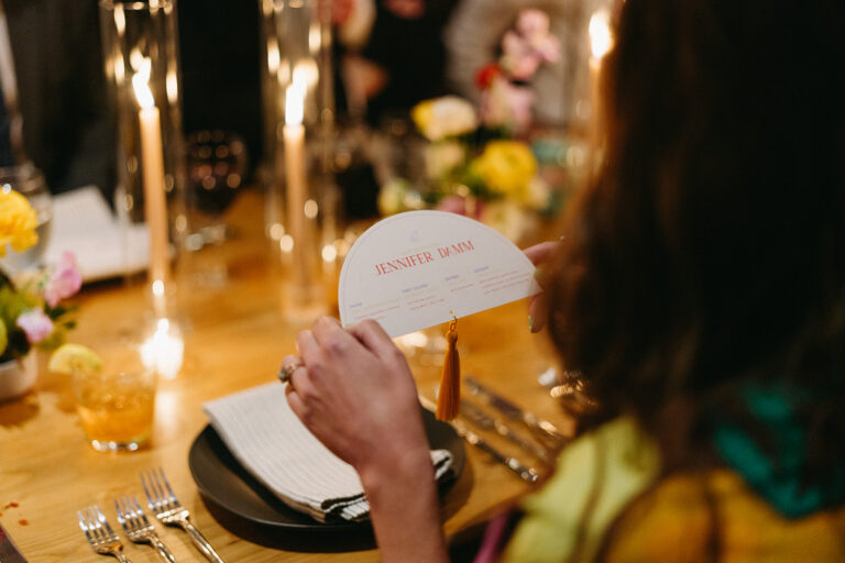 Guest holding a personalized menu at a candlelit New Orleans wedding dinner