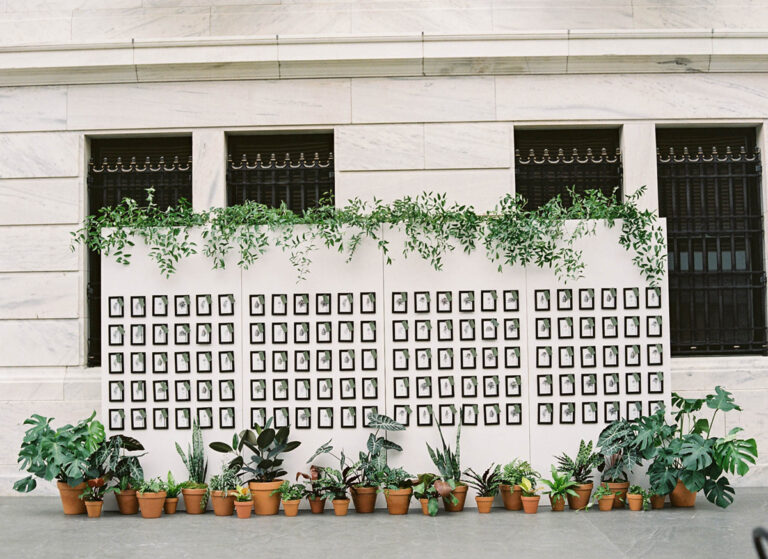 Botanical escort card display with framed sketches and potted plants