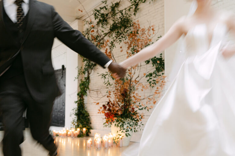 Newlyweds holding hands beside candlelight and autumn greenery at a Cleveland wedding