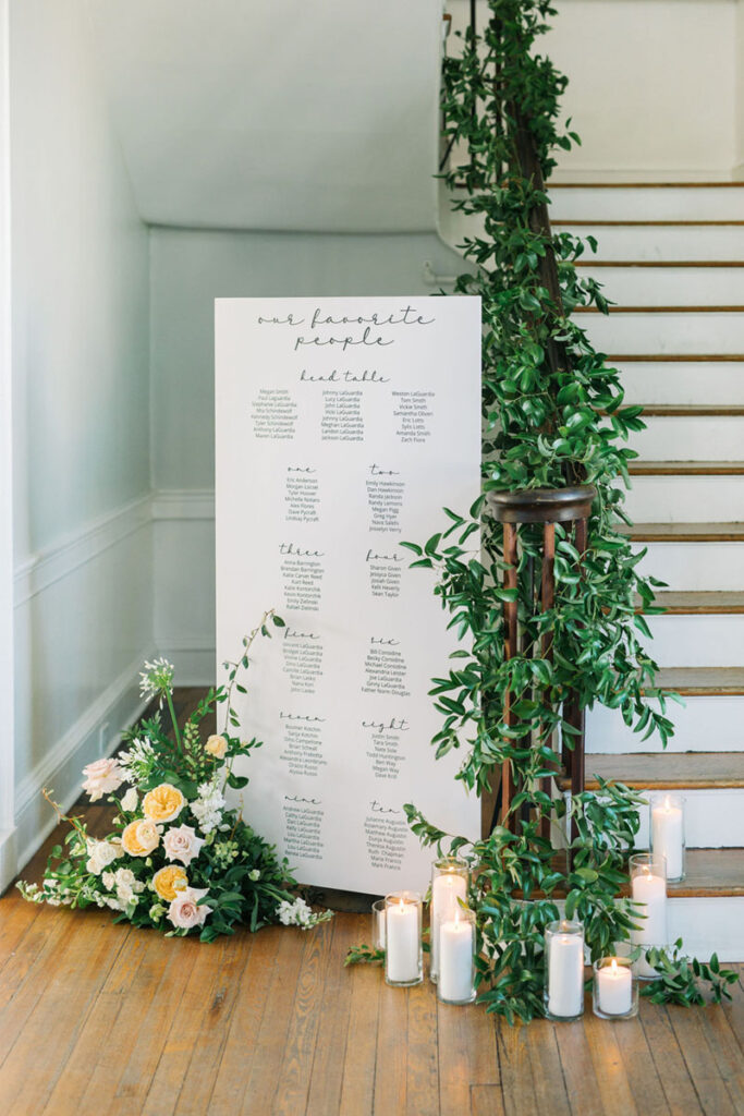 Wedding escort display with flowers, greenery, and candlelight