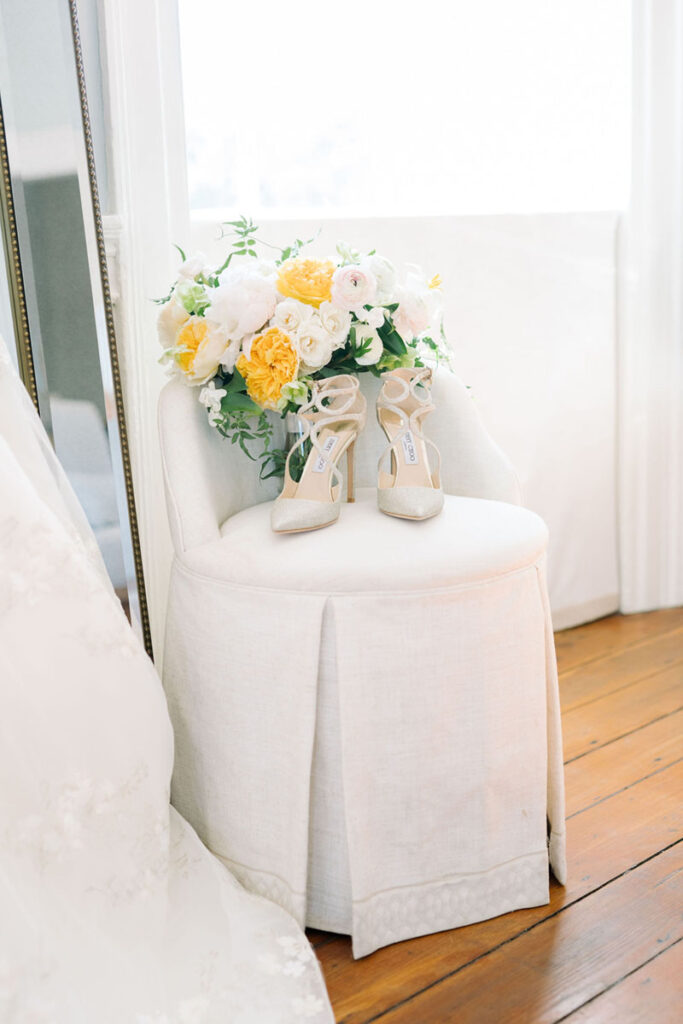 Bridal bouquet and wedding shoes arranged beside the bride's gown