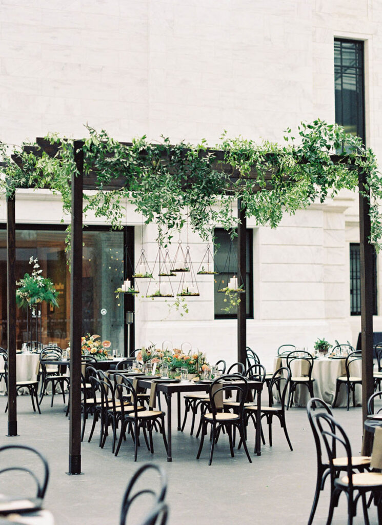 Greenery-covered pergola above elegant wedding reception tables