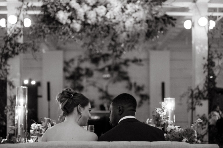 Newlyweds seated beneath suspended florals at a November wedding at Gordon Green