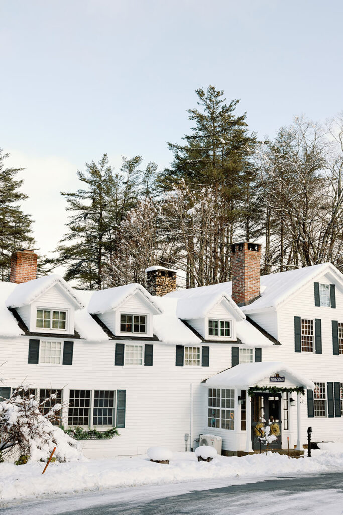 Snow-covered New England inn surrounded by evergreen trees in Vermont