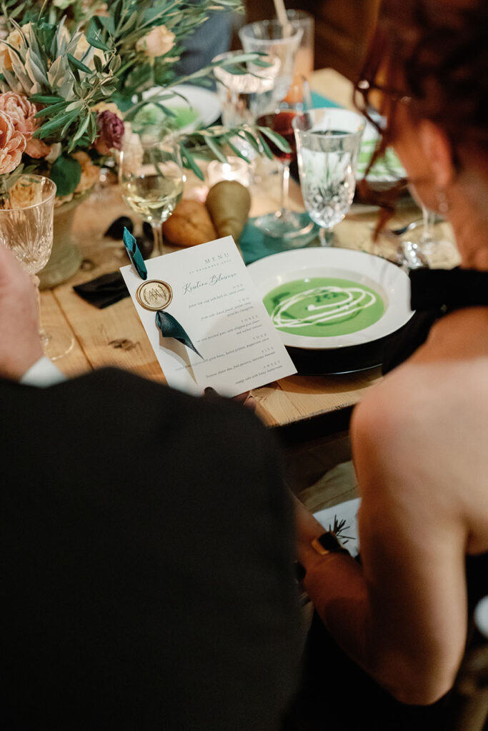 Guests reading a wax-sealed dinner menu at an intimate Vermont wedding