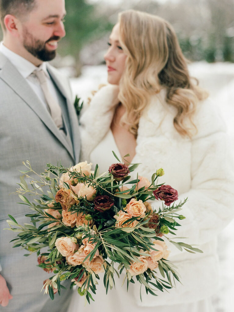 Bride and groom with a peach and burgundy winter bridal bouquet in Vermont